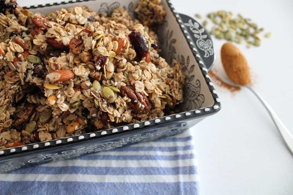 Best Crunchy and Chunky Granola in a baking dish with a tablespoon of cinnamon