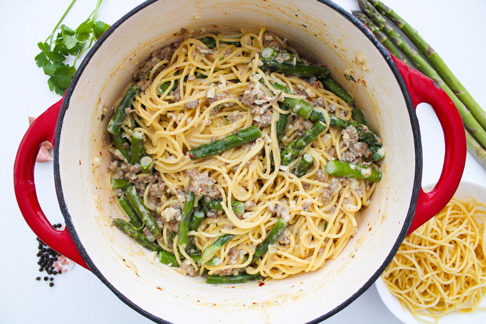 creamy sausage asparagus pasta in red dutch oven