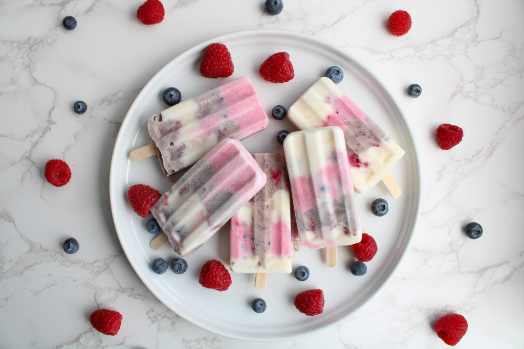 Healthy 4th of July Popsicles pops on a plate with berries
