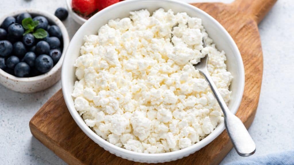 cottage cheese in a bowl with spoon and berries on the side