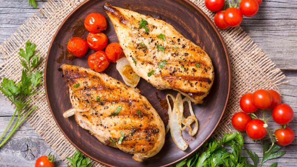 2 grilled chicken breasts with cherry tomatoes on a plate