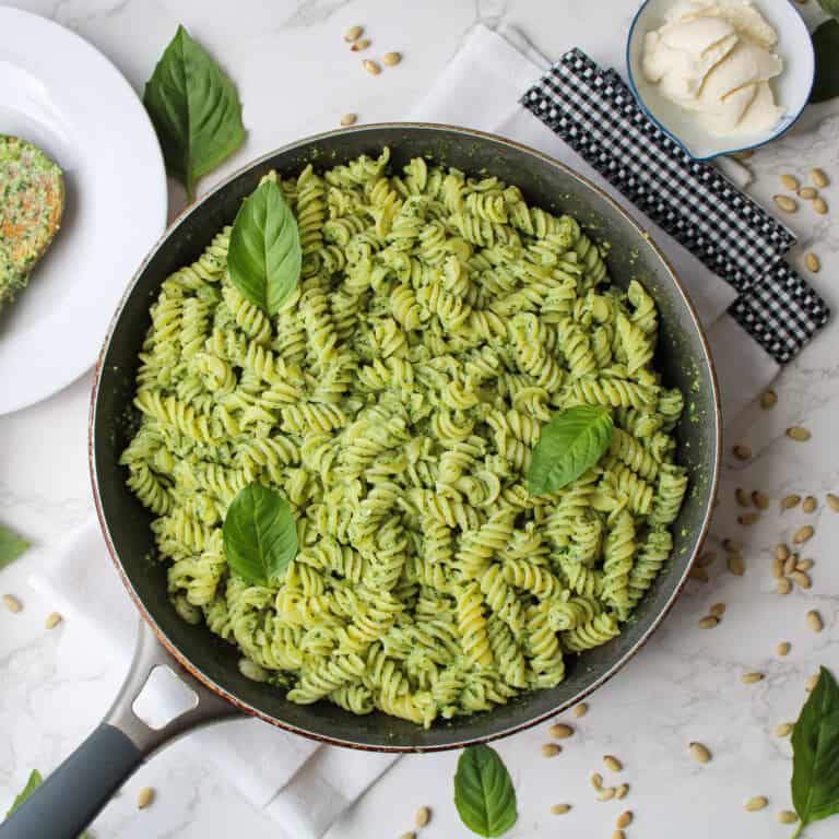 Ricotta pesto pasta in a large frying pan garnished with fresh basil