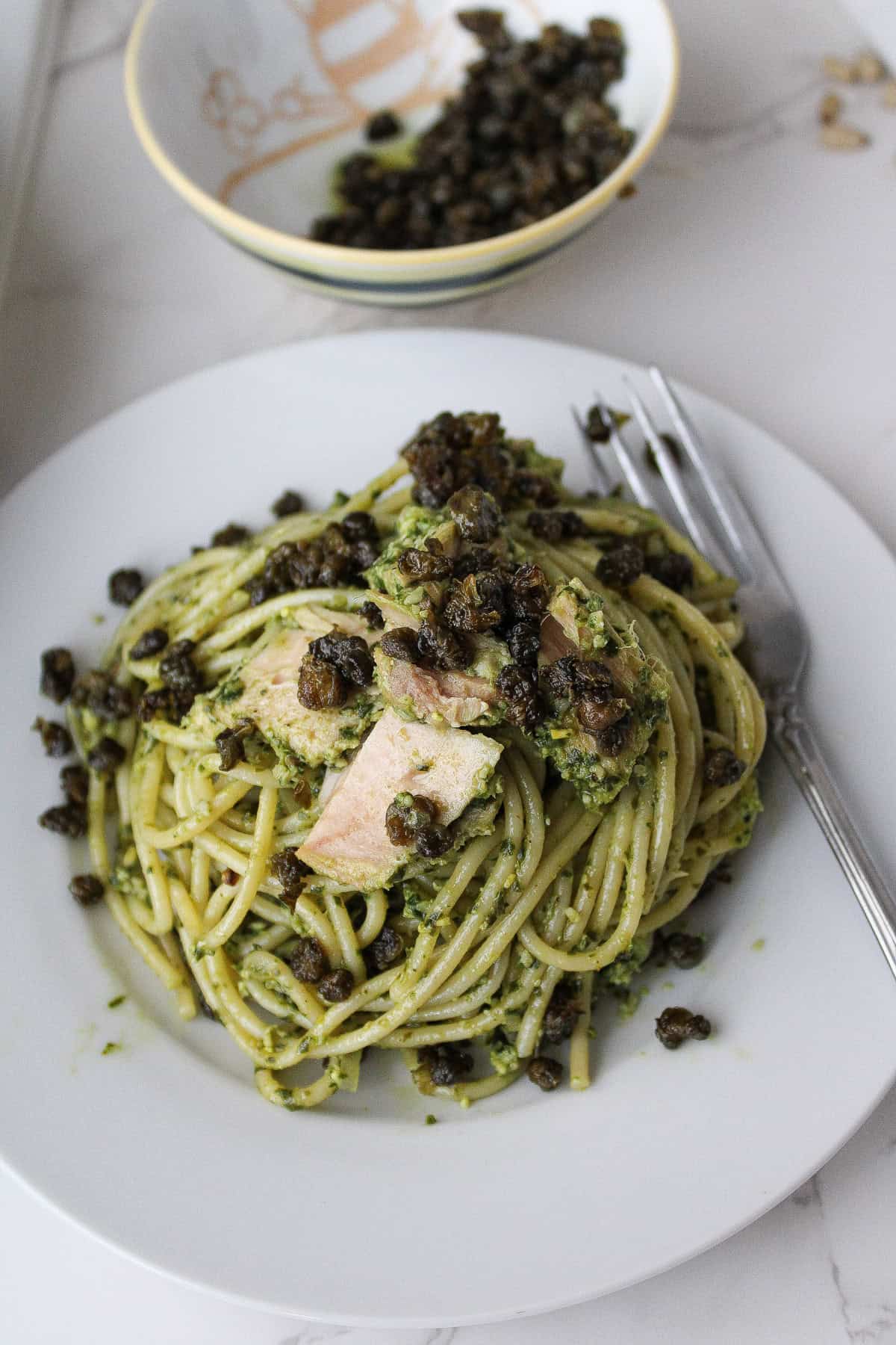 close up view of pesto pasta with tuna and fried capers